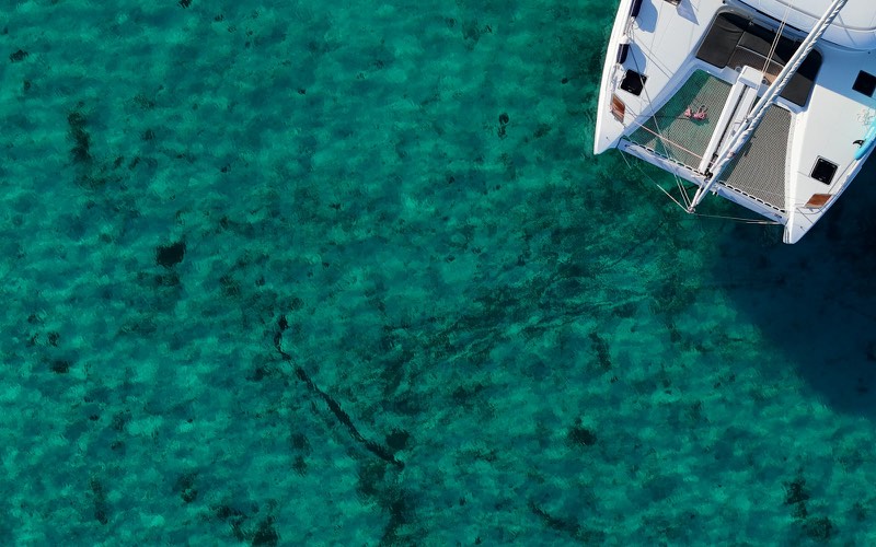 Catamaran anchored over turquoise water, seen from above